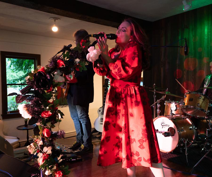 A singer and two players mid-performance on the gallery stage