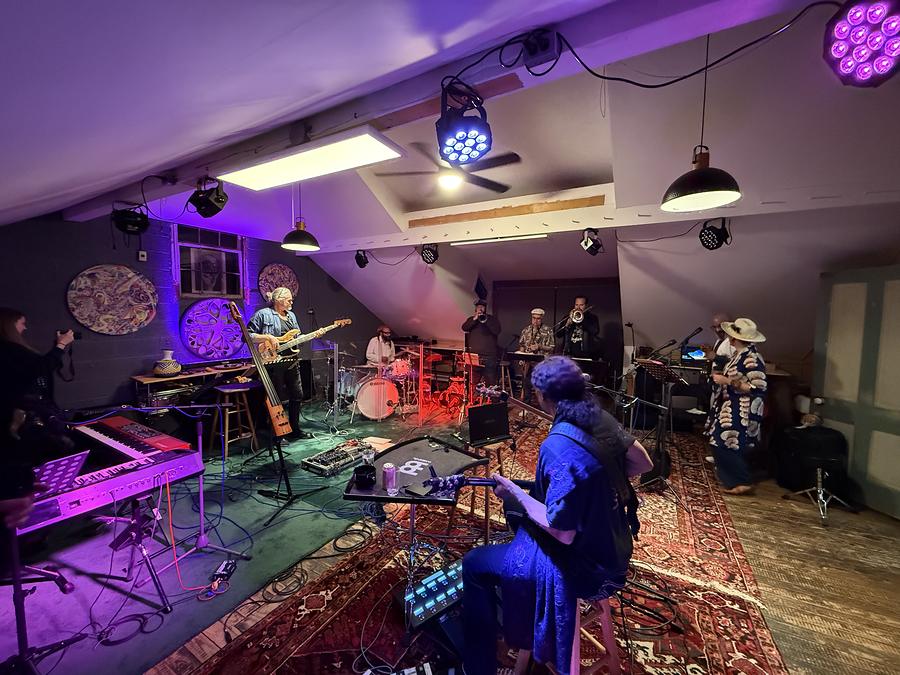 Musicians playing together late in the jam room under coloured light