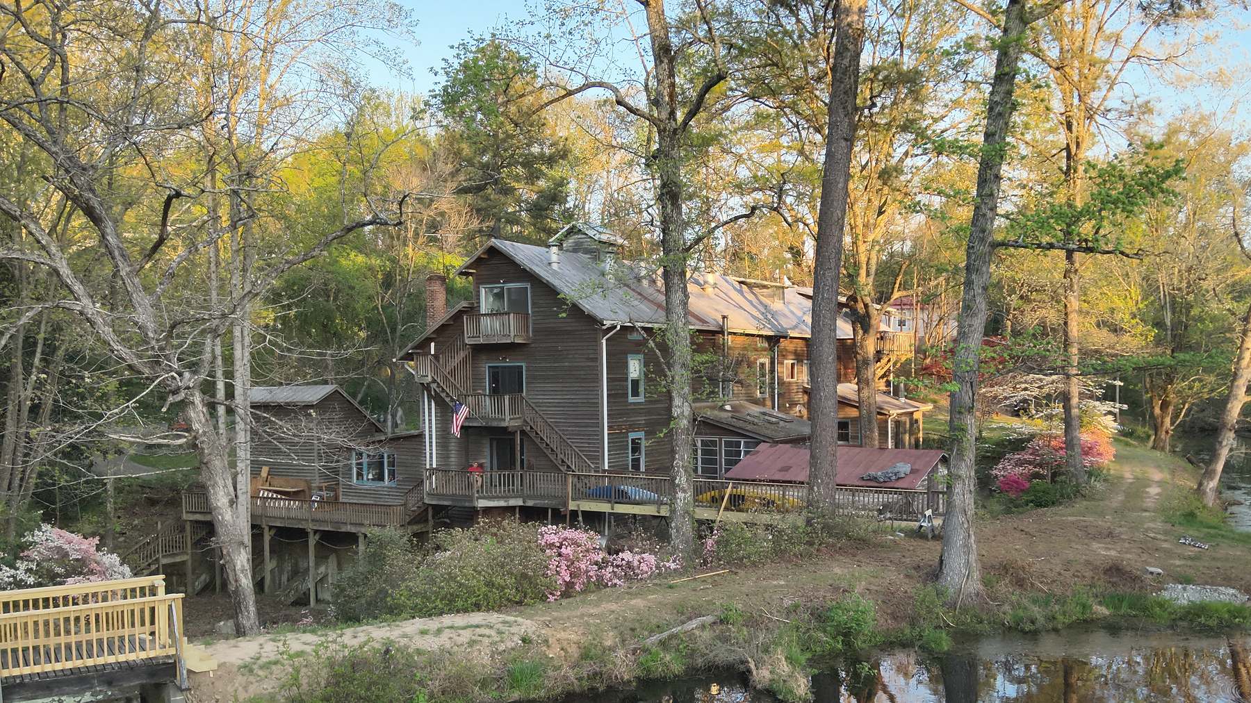 The mill and its outbuildings above King's Pond, azaleas and dogwood in bloom along the bank