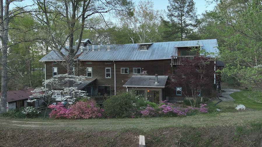 The mill buildings seen across the water, flowering azaleas along the near bank