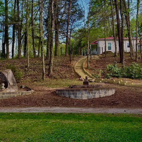A cottage among the pines, a stone millwheel set in the clearing in front of it