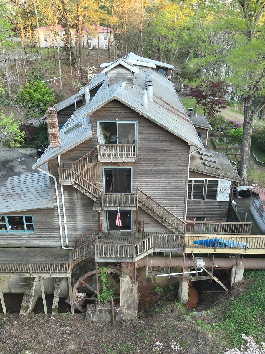 The mill from above — weathered timber, tin roofs, and decks stepping down to the water